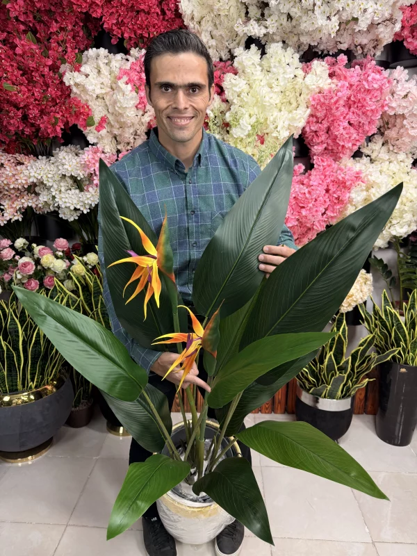 درختچه مصنوعی پرنده بهشتی قرار گرفته در یک گلدان شیک در گوشه پذیرایی به عنوان گیاه دکوری.