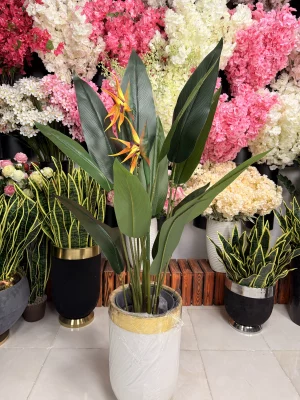 درختچه مصنوعی پرنده بهشتی قرار گرفته در یک گلدان شیک در گوشه پذیرایی به عنوان گیاه دکوری.