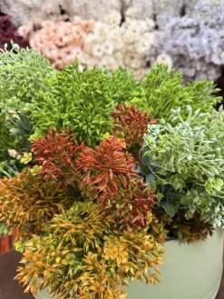 بوته مصنوعی قاصدک قرمز رنگ در یک گلدان سفید مدرن روی میز کار در کنار لوازم اداری