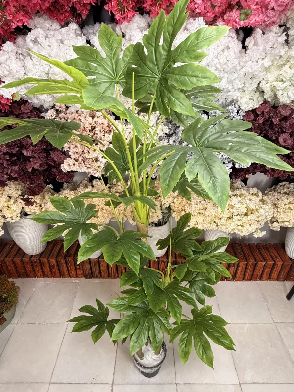 تصویر نزدیک از برگ‌های لمسی درختچه آرالیا مصنوعی، با نمایش رگ‌برگ‌های زرد و جزئیات دقیق و طبیعی.